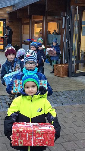 Sie wollen armen Kindern ein Weihnachtsgeschenk machen: die Vorschulkinder der Kita St. Nikolaus bringen ihre liebevoll verpackten „Geschenke mit Herz“ zum Lieferfahrzeug. Foto: Kath. Kita IN gGmbH