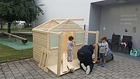 Eltern und deren Kinder helfen beim Bau des Spielhauses zusammen. Foto: Kath Kita In gGmbH/Schmidt