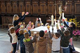 Die Kinder der Kita gGmbH feiern einen rhythmischen Wortgottesdienst im Münster. Ein meditativer Blütentanz des Kindergartens Stangassinger um den Altar. Foto: Kita-GmbH/Schödl