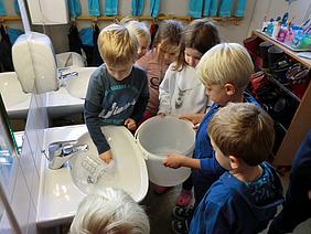 Die Kinder sind gespannt, wie viel Wasser sie beim Händewaschen verbraucht haben. Foto: Sebald/Kath. Kita IN gGmbH